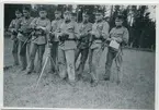 Ett tiotal militärer i fältmiljö,skogsbryn.