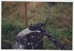 Närbild kedjefäste på sten som omger minnessten