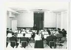 Ett tjugotal blåsmusiker övar med militär musikledare.