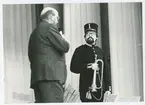 Torsten Lorentzon talar med militärmusikant på scenen.