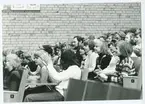 Applåder och skratt från grundskoleelever som förmodligen är
publik till militärmusikföreställning.