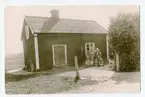 Familjen Forsbäck står fram för soldattorp nummer 106, Skänninge Kompani under Appuna Söder- och Mellangård i Appuna socken. Korpral Gustaf Erik Forsbäck hade antagits som soldat 1901 och flyttade då in i detta torp. Han gifte sig påföljande år med Anna Olivia Eriksson och de kom att få elva barn varav det sista föddes i januari 1922 och fick namnet Gunnar Elving Forsbäck. Rimligen är fotot taget 1922.