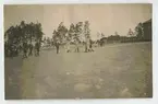 Några officerare rör sig över stenlagt inhängnat område.
(invigning av 2:a Livgrenadjärreg.1923).