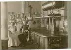 Fotografi från 1911 i militärskolans kök. Gåva av fabrikör H.
Hellström, Österbymo. H (stående till höger på bilden) tjänstgjorde
som kock under sin värnpliktstid samma år.