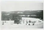 Utsikt över trähus,vita vidder,skog och fjäll.