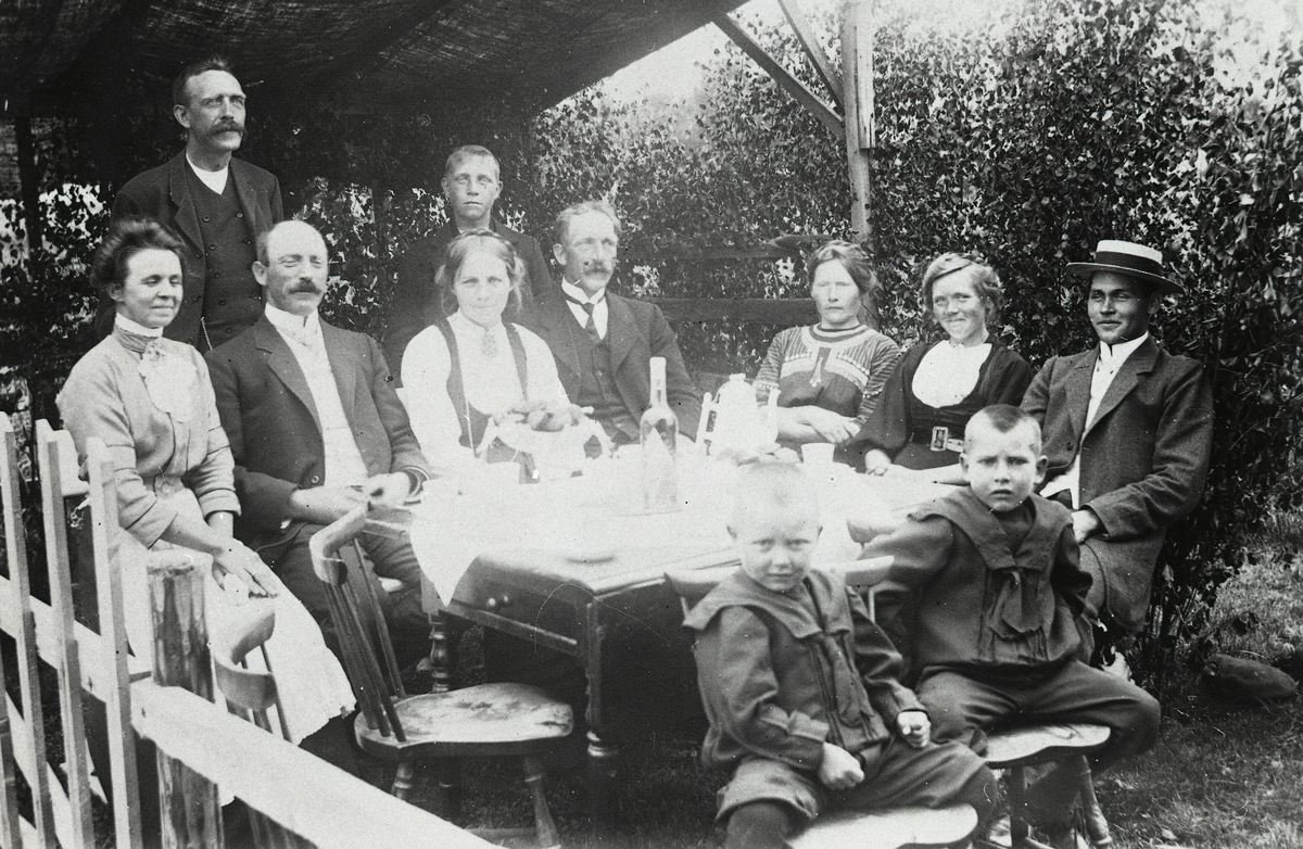 Familieselskap i lysthuset på Krossvegen i Bø.  F.v Anna Sagen, sarpsborg, Hans Sisjord ståande, Halvor H. Sagen f. 1874 d. 1955, Sarpsborg, Kari O. Saga f. 1889 d.1976, Olav H. Saga f. 1876 d. 1963, Johannes Saga ståande bak, f. 1897 d. 1981, Mari H. Saga f. 1882 d. 1973, Ronnaug Saga f. 1888 d. 1976, Kittil H. Sagen. Sitjande framme f. v Erik K. Sagen f. 1907 og Håkon K. Sagen f. 1905, begge Sarpsborg.