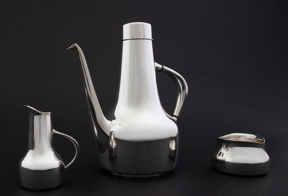 Kaffeservise i tre deler, utført i sølv. Samtlige deler er glattpolert, uten dekor og med mykt avbuede kanter. 

1) Kanne med sylinderformet kompakt korpus, som glir over i en konisk langstrakt hals. Fra korpus løper en lang tynn tut, som er mykt buet. Det sirkulære lokket fremstår som en forlengelse av halsen, men overgangen er markert med en ringformet vulst. Den buede haken løper fra korpus til øvre del av halsen, og før ansatsene er det plassert to ringformede lameller av presstoff for varmeisolering. 

2) Fløtemugge med sylinderformet kompakt korpus, som glir over i en konisk langstrakt hals, som avsluttes i et nebb. Muggens buede hank løper fra korpus til midten av halsen.Sukkerkopp med oval grunnform, og buet kant øverst. 

3) Sukkerkopp med oval grunnform, og buet kant øverst.