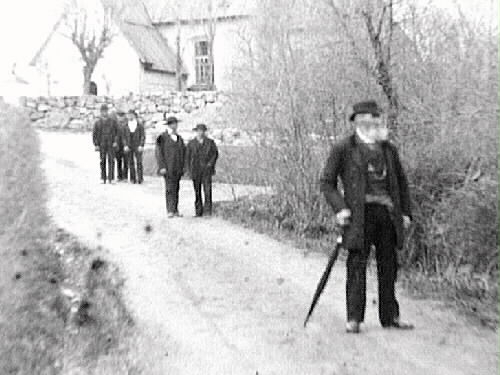 Människor som går på vägen från en kyrka någonstans i Halland.