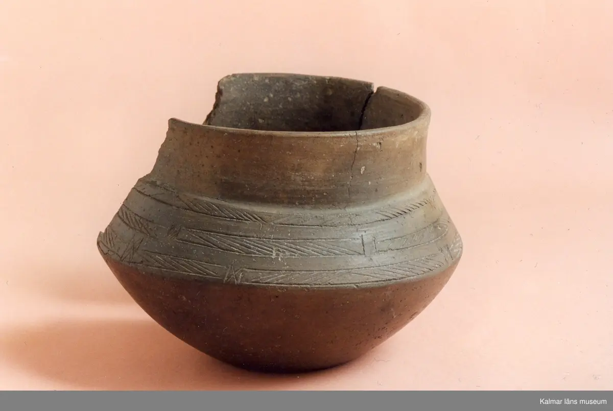 KLM 2846. Gravurna. Kärl av lera med skarpt svängda bukkanter, godset är tunt, fast och till färgen rödbrunt, under den vertikala mynningsdelen är ornerat med tre i omväxlande riktning snedsträckade band, vilka är lätt tecknade i leran.