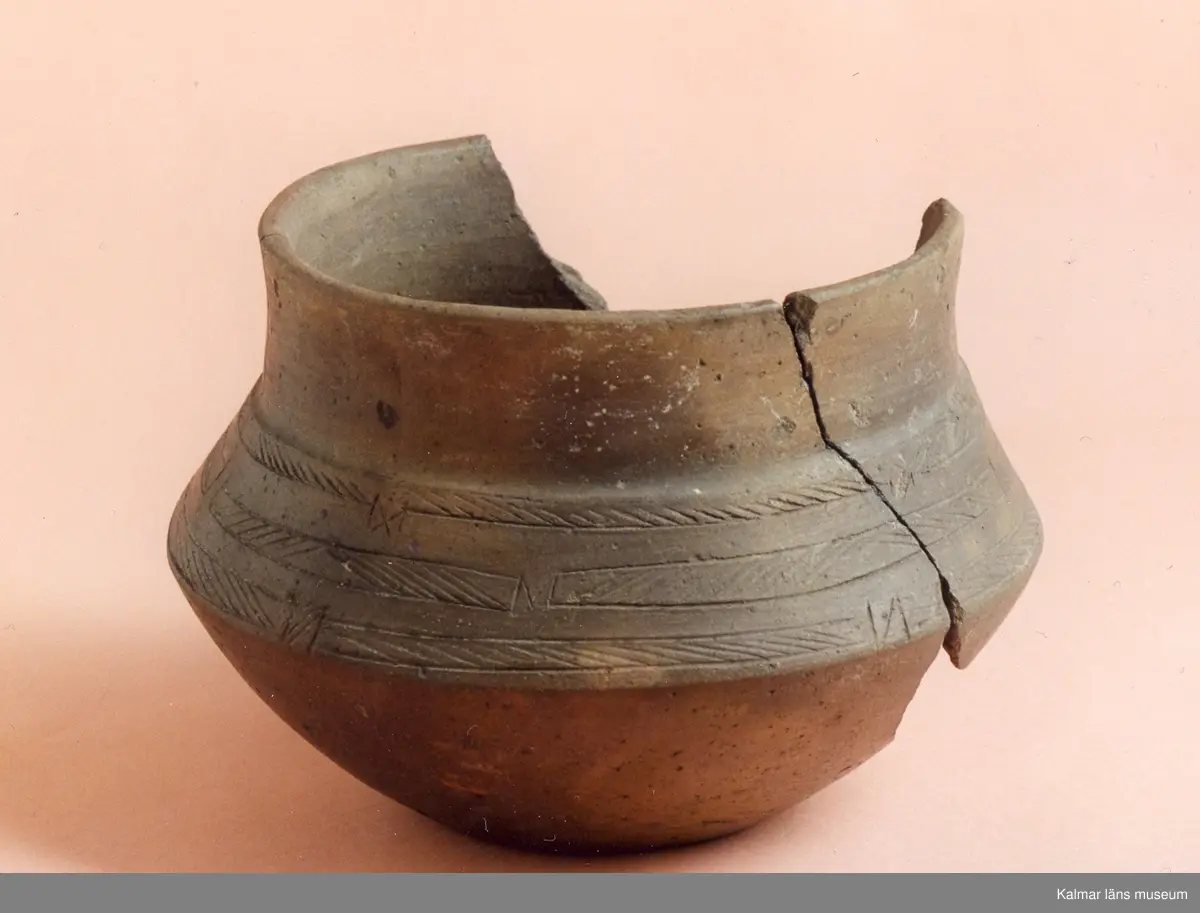 KLM 2846. Gravurna. Kärl av lera med skarpt svängda bukkanter, godset är tunt, fast och till färgen rödbrunt, under den vertikala mynningsdelen är ornerat med tre i omväxlande riktning snedsträckade band, vilka är lätt tecknade i leran.