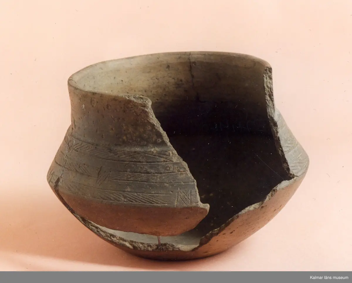 KLM 2846. Gravurna. Kärl av lera med skarpt svängda bukkanter, godset är tunt, fast och till färgen rödbrunt, under den vertikala mynningsdelen är ornerat med tre i omväxlande riktning snedsträckade band, vilka är lätt tecknade i leran.