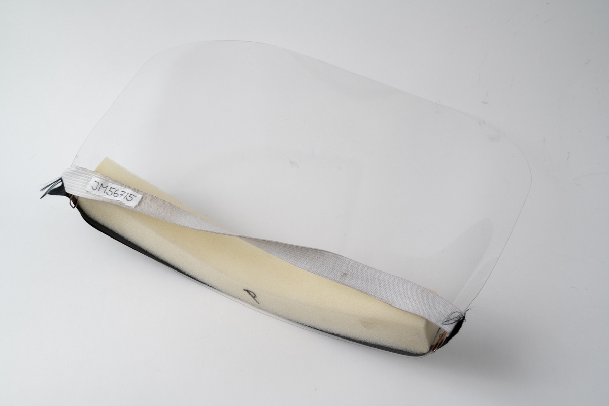 Visir av genomskinlig plast, heltäckande för ansikte. Ett avlångt stycke skumplast är fäst på baksidan av övre kanten på visiret, för placering mot pannan. Visiret hålls på plats med elastiskt resårband mot bakhuvudet. Resårbandet är fäst i visiret med en metallklammer i var sida. Över skumplastremsan är ett svart band med guldtexten "Interflora" fäst med gem i var ände. På skumplasten är textat: "P", vilket betyder Pelle, visirets användare.

Artikelnummer: ZSKYVIS0003.

Se vidare Historik.