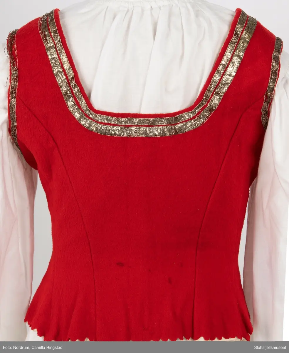 Liv med innsydde spiler. Hekter på hver side av åpningen foran. Gyldne bånd påsydd 