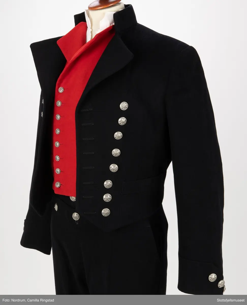 Svart jakke med dobbelrekke knapper. Sølvknapper på lukkingen og på ermene.