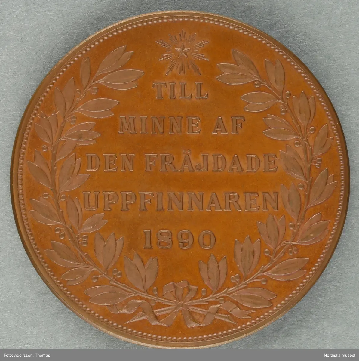 Huvudliggaren:
"Minnespenning. I koppar. Å åtsidan löses 'JOHN ERICSSON FÖDD I SVERIGE D. 31 JULI 1803 * DÖD I N AMERIKA D. 8 MARS 1889.', 'A. LINDBERG', 'A.F. WESTERLUND DIR.', å framsidan: 'TILL MINNE AF DEN FRÄJDADE UPPFINNAREN 1890'.
G. af ingeniör A. F. Westerlund i Stockholm 12/10 1890."