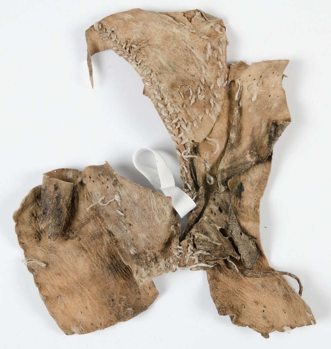 Fragment av pälsplagg. Eventuellt del av ärmhål, sidostycke och bakstycke. Osäkert vad det varit del av för plagg.
