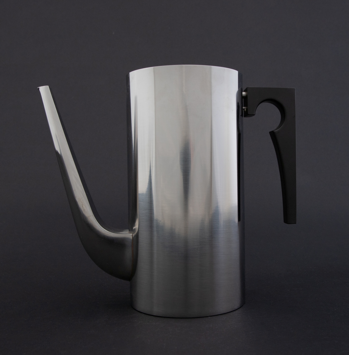 Cylinda-line kaffekanne i rustfritt stål med håndtak av svart kunstsstoff. Korpus er høy, sylinderformet med lang tut som er festet nederst på korpus. Lokket er løst med en sirkulær, flat lokknapp.