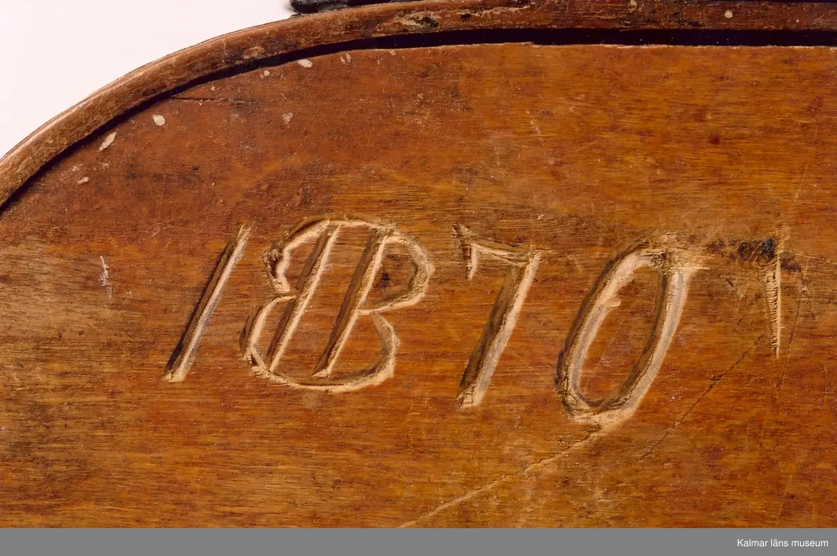 KLM 6754. Äska, svepask med knäpplock och litet handtag på locket. Av böjt bokspån, oval. Ornerad med punktlinjer i geometriskt mönster. Målad helt i mörkgrönt. På lockets insida inskuret 17692 (76 -ihopskrivet), under botten inskuret 1870.