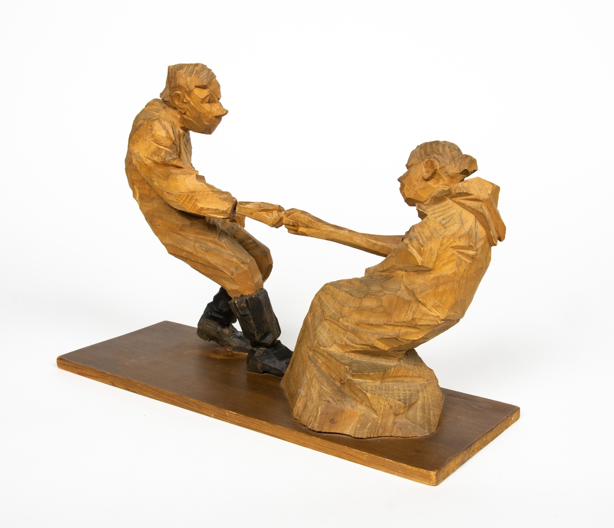 Skulptur i trä av Döderhultarn. Skulpturen föreställer två figurer, en man och en hustru i en dragkamp, så kallad ”fingerkrok”. På figurens fotplatta finns en dedikation: ”Från Axel Petersson till Flygaren å vännen Rodéhn 2/9 1919. En ringa gärd af tacksamhet för tvänne i allo förstklassiga ”himmelsfärder”. Länge lefve Br Rodéhn!!! D.S".
Jämte dedikationen finns konstnärens signatur synlig i form av en stämpel.