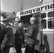 Två män står och pratar utanför en buss. På bussen står det Husqvarna.
