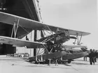 Flygplan Sk 4, Heinkel HD 24, med flottörer står uppställd på vagn utanför en hangar. Tre män står vid flygplanet.