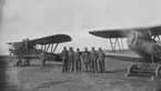 Militära flygmekaniker och flygare står vid flygplan S 1, FVM S 21, nummer 3204 och flygplan Sk 5 med motorn igång. Åtta män. På F 5 Krigsflygskolan i Ljungbyhed. 1926-1929.