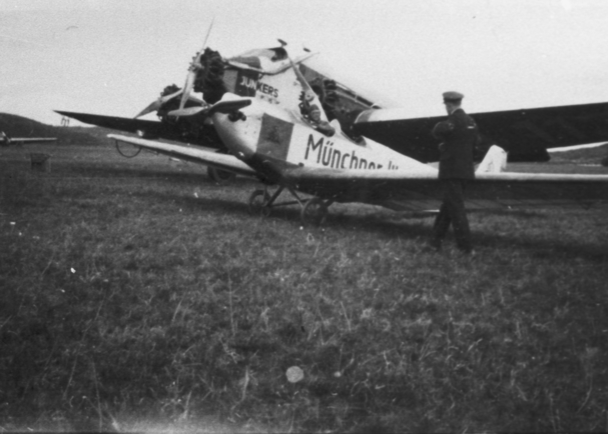 Civilflygplan Daimler L20 B I registreringsnummer D-977, med reklamtext "Münchner Illustrierte II" samt flygplan Junkers G31ce, registreringsnummer D-1137 står på Torslanda flygplats vid Nordiska flygarmötet den 29 maj 1927. Vy från sidan.