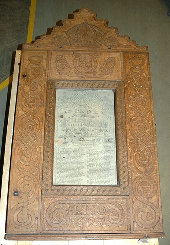 a) Skåp. Framsidan dekorerad med plattrelief, stiliserade bandmotiv, rankor mm. Carl XI:s monogram 1693. Krön med krona och vindruvsklasar. Rektangulär glastäckt öppning b) Täckt fröjdekväde 