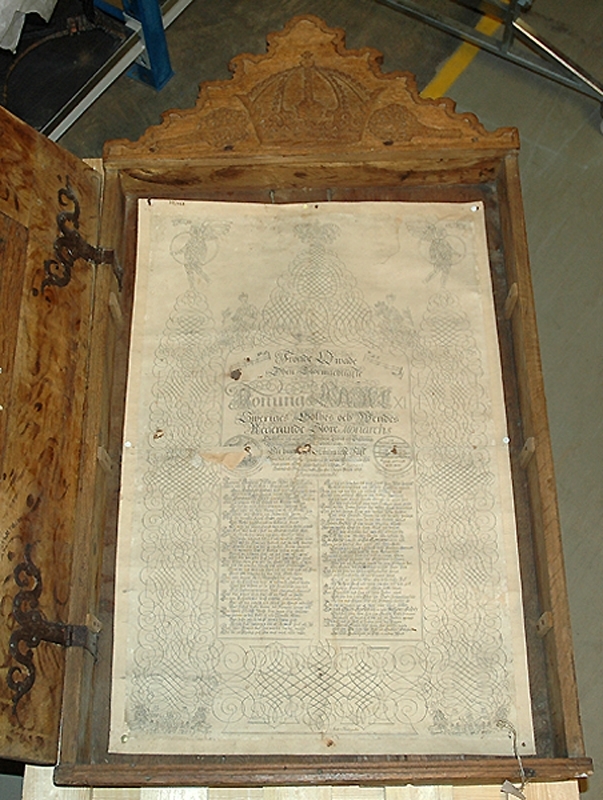 a) Skåp. Framsidan dekorerad med plattrelief, stiliserade bandmotiv, rankor mm. Carl XI:s monogram 1693. Krön med krona och vindruvsklasar. Rektangulär glastäckt öppning b) Täckt fröjdekväde 