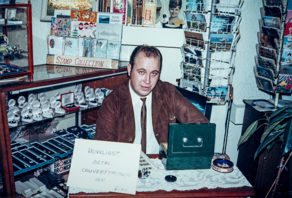 Ole Eilif Sveen (1942-1991) fra Ottestad, sittende med "billettsalg" / inngangspenger / kuværpris til et arrangement ved Steinrøysa bar på Velferdsklubben i Yokohama i Japan. Der han arbeidet i perioden 1973-1976. Resten av sitt yrkesaktive liv var han sjømann. 
Velferden, Statens Velferdskontor for Handelsflåten.