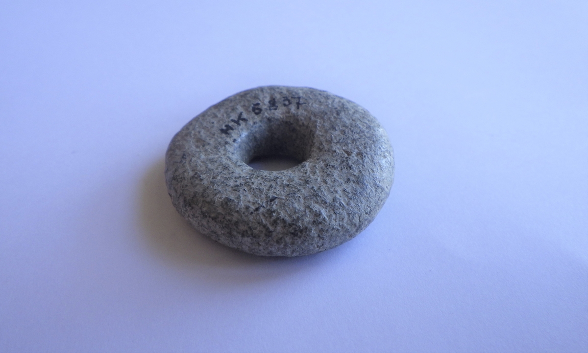 Spinnehjul i stein med flat over- og underside, og buede kanter.