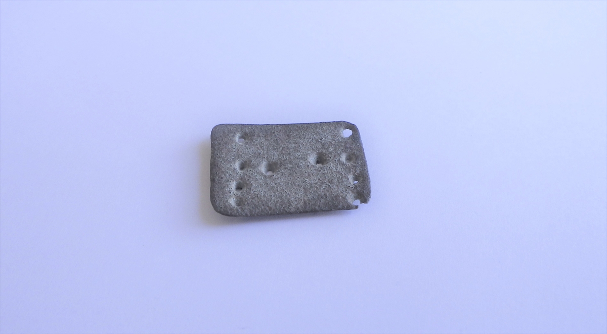 Ti punslede punkter satt opp med fire på linje i hver av kortendene og to langs midten av platen. Til sammen gir de form av en majuskel H.