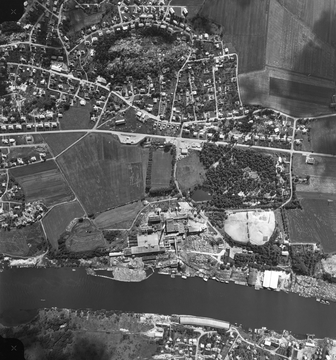 Flyfotografi tatt over tettstedet Torp og hjørnesteinsbedriften Torp Brug i Borge kommune i Østfold, antakelig i 1950-åra.  Bildet er tatt fra forholdsvis stor høyde, rett ned mot det underliggende landskapet.  Dersom bildet holdes med sørsida ned og nordsida opp, ser vi Glomma i vest, mot venstre bildekant.  På vestsida av elva ser vi takene og bordtomtene på Hauge Bruk,som lå i Rolvsøy kommune, og vi ser også noe av småhusbebyggelsen der mange av arbeiderfamiliene som var knyttet til Hauge Bruk bodde.  Ettersom bordtomtene ved denne trelastbedriften var tomme, er det sannsynlig at fotografiet ble tatt etter at virksomheten var avviklet.  På østsida av Glomma, rett over for Hauge Bruk, ser vi ned på fabrikkbygningene og de omliggende tomtearealene til Torp Brug, som var en treforedlingsbedrift med kraftpapir som hovedprodukt.  Kalkdeponiene på den søndre delen av arealet skiller seg ut med sine lyse overflater.  I elveløpet skimter vi en del tømmer som var innlenset ved elvebredden, slik at det kunne tas inn på sagbruket hvor stokkene ble kappet i høvelige kubblengder for flishogging og derpå følgende cellulosekoking og papirproduksjon.  Torp Brug var bygd på jordbrukseiendommen Søndre Torps grunn, og mye av åkerjorda var fortsatt ubebygd da dette fotografiet ble tatt.  Sørøst for fabrikken var det en liten furuskog, som delvis var pleiet som parkområde, og sør for denne grønne lunga skimter vi takene på de flotte murvillaene som var bygd for funksjonærer som var sentrale i fabrikkledelsen.  Mange av fabrikkarbeiderfamiliene bodde på Torpeberget, en grunnlendt granittrygg nord og øst for fabrikken.  Her var det også skole, forsamlingslokale, meieri og forretninger.  Mellom fabrikkanlegget og riksveg 111, som går nord-sør i dette bildet, ser vi fotballbanen til Torp Idrætsforening.

En kort historikk om Torp Brug finnes under fanen «Opplysninger».