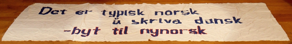 Banner frå arkivet til Norsk Målungdom. På banneret står teksten: "Det er typisk norsk å skriva dansk - byt til nynorsk". Det er truleg at banneret har vore i bruk under ein aksjon for Norsk Målungdom.