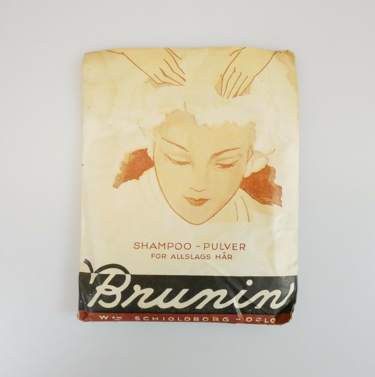 En kvinne med innsåpet hår. Over henne to hender som tar på håret hennes. 