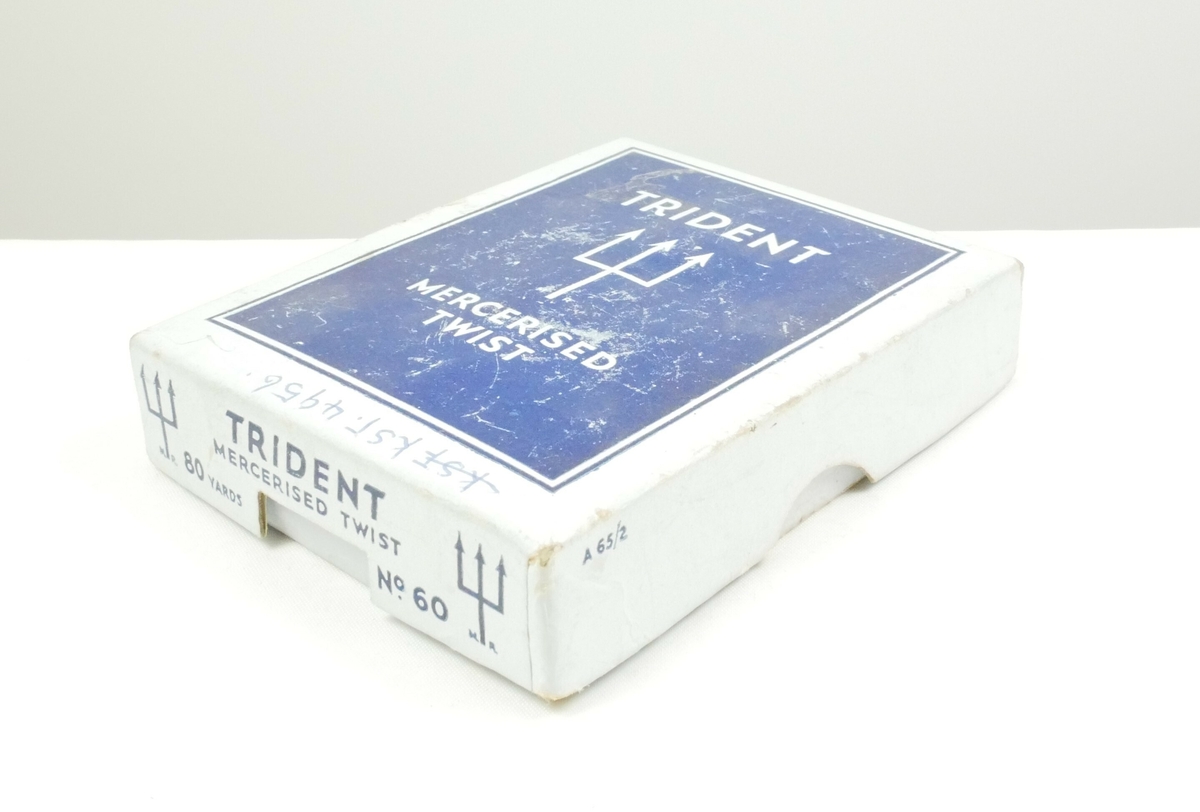 Hvit rektangulær pappemballasje med lokk. Inne i esken er det tre halskjeder. 

Halssmykke med gule steiner. 

Halssmykke to tekstiltråder med hvite steiner, en lås i enden

Gullfarget halssmykke 