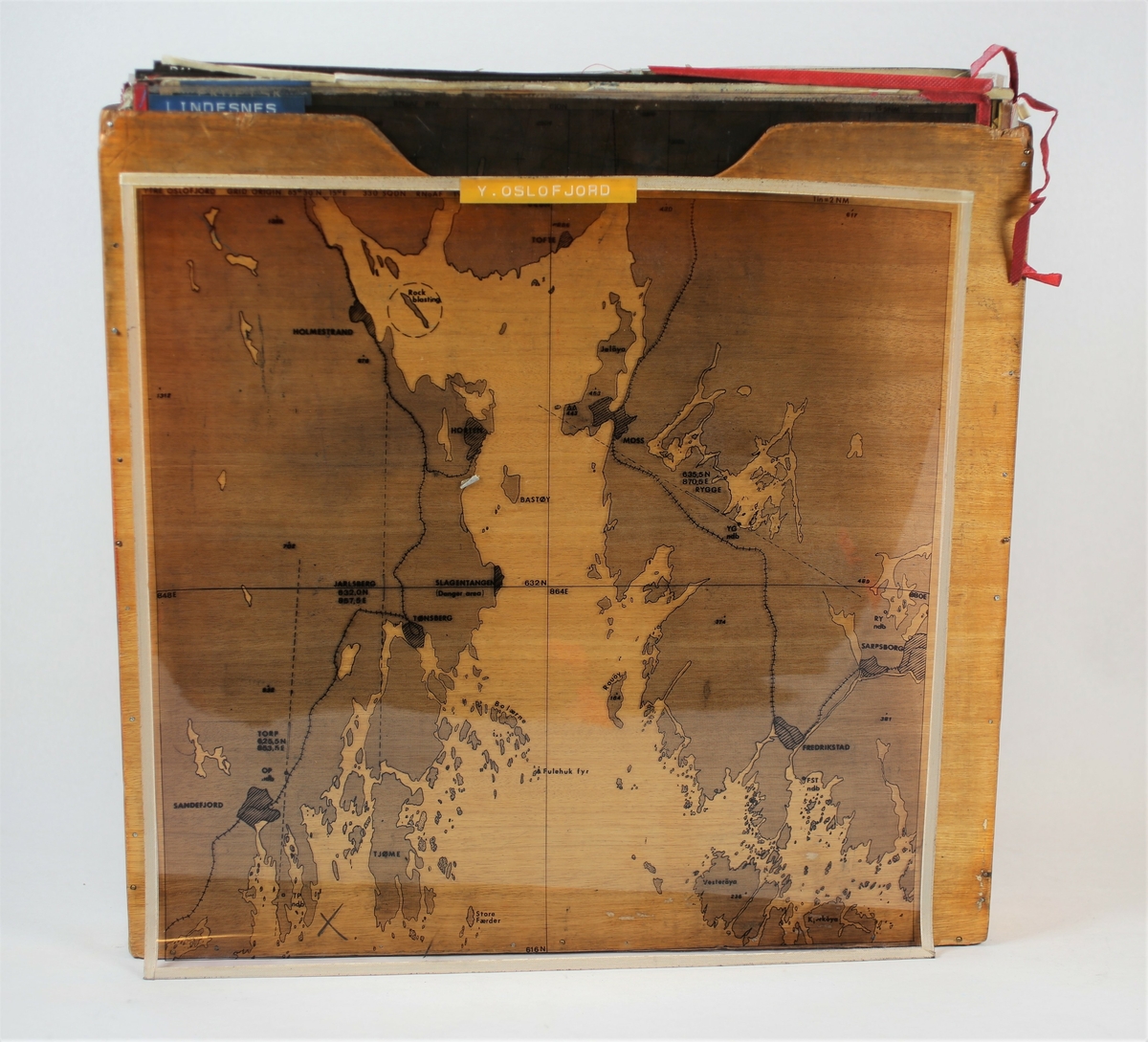 Kartmappe som inneholder kart, overlays og annen informasjon som er nødvendig for navigatør i Sea King redningshelikopter. Mappen inneholder også en innsats i tre for oppbevaring av plastoverlays. 