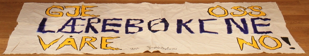 Banner frå arkivet til Norsk Målungdom. På banneret står teksten: "Gje oss lærebøkene våre no!". Det er truleg at banneret har vore i bruk under ein aksjon for Norsk Målungdom.