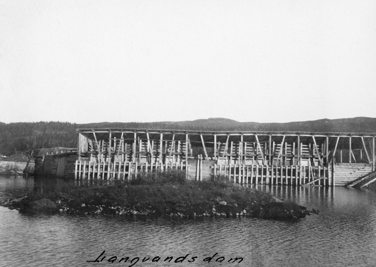 Den gamle Långevassdammen eller Langevannsdammen i Skirvavassdraget i Tinn i Øst-Telemark.  Dette var en diger trekonstruksjon, som hadde 16 lukeløp og to nåleløp.  På dette fotografiet er det først og fremst lukeløpene vi ser.  De var plassert mot ei dambru med en overbygning – en bindingsverkskonstruksjon med pulttak.  Her ble vannstanden regulert ved å heve eller senke luker, langs vertikale sleider på motstrøms side av dammen.  Nåleløpene skimtes til venstre i bildet.  Her ble dammen stengt ved hjelp av «nåler», planker som ble stukket tett i tett motstrøms slik at de ble presset mot en terskelstokk og dambrua, der de dannet en tett vegg for vannmassene.  Dette fotografiet er antakelig tatt omkring 1920.  I perioden 1922-1925 ble nemlig den avbildete dammen erstattet av en tørrmurt steindam, murt av bruddstein, og med et ti meter bredt damløp med såkalt «segmentluke».   Långevassdammen lå cirka 15 kilometer fra Skirvas utløp i Tinnsjøen.  Dammen var følgelig primært en reservoardam, brukt til å regulere vannføringa i det nedenforliggende vannløpet til beste for fløtinga, eller «brøtninga» som denne virksomheten i sideelvene ble kalt i denne regionen.  Der var nemlig fløterne avhengige av forholdsvis store vannmengder for å få tømmeret nedover et forholdsvis trangt og vanskelig elveløp, hvor stokkene ellers hadde lett for å binde seg i hauger.  I fossene helt nederst mot Tinnsjøen forekom det dessuten en god del brekkasje.  Skirva var fløtbar over en distanse på cirka 25 kilometer, men i de to øverste av de seks fløtingsrotene ble det ikke levert virke hvert år.  Långevassåe eller Langvassåa, som førte vannet cirka en kilometer fra denne dammen mot hovedvassdraget rant inn i Skirva ved grensa mellom tredje og fjerde rote.  Vannet fra den avbildete dammen bidro altså til å lette fløtinga over en distanse på drøyt femten kilometer nederst i dette vassdraget.