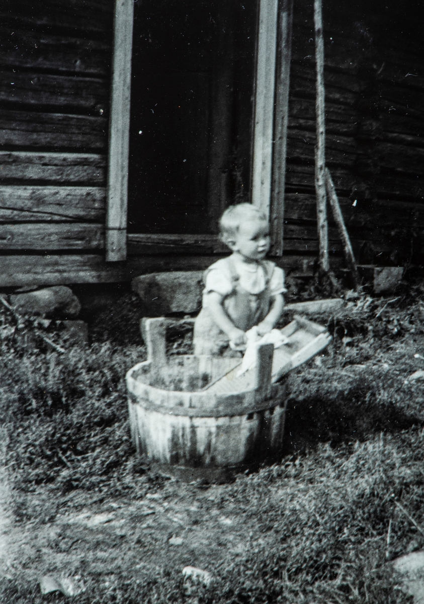 Ukjent barn ved en vaskestamp, vaskebrett. Klesvask. 
Bilde hentet fra et album med bilder i fra Vallset og Ottestad området.