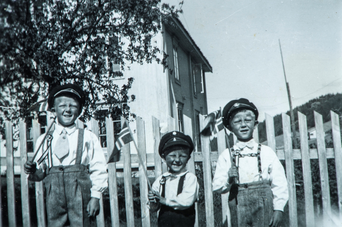 Gruppe 3 festkledde barn med norske flagg og uniformsluer, Ove, Gunnar og Arild Mæhlum på Hvalsbakken i Vallset, 17. mai ca 1949.