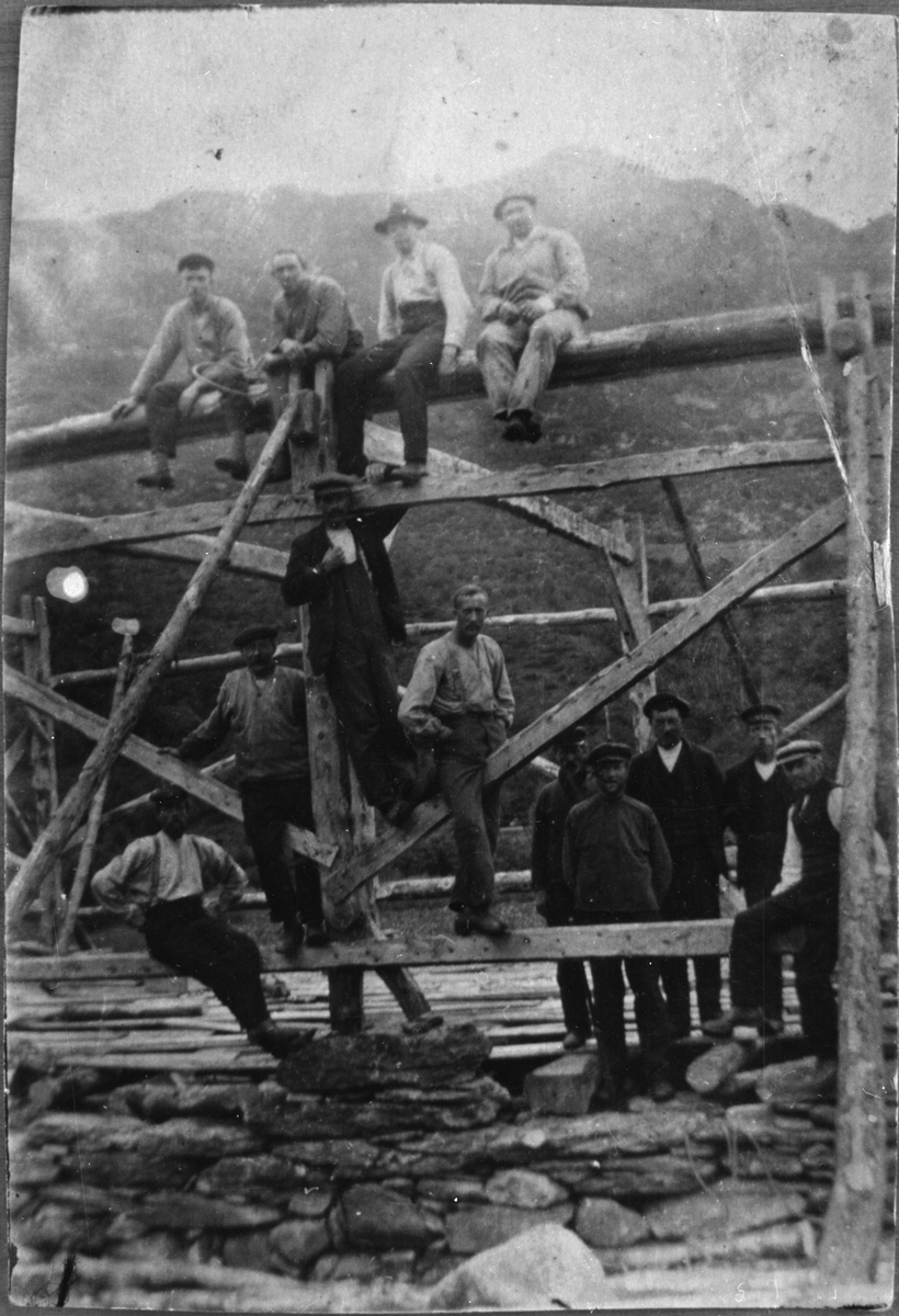 Bygging av løe på Heiabø i Ølen, ca. 1915. Sitjande øvst, frå venstre: Berge Klungland, Henrik Olsen, Ole Klungland og Simon Olsen. Nede, frå venstre: Johannes J. Heggebø, Thomas Skålnes, Osmond A. Skålnes, Gunnar Dørheim, Per Stumo, Bent Heggebø, Jens Hårde, Nils A. Skålnes og Tollef Klungland.