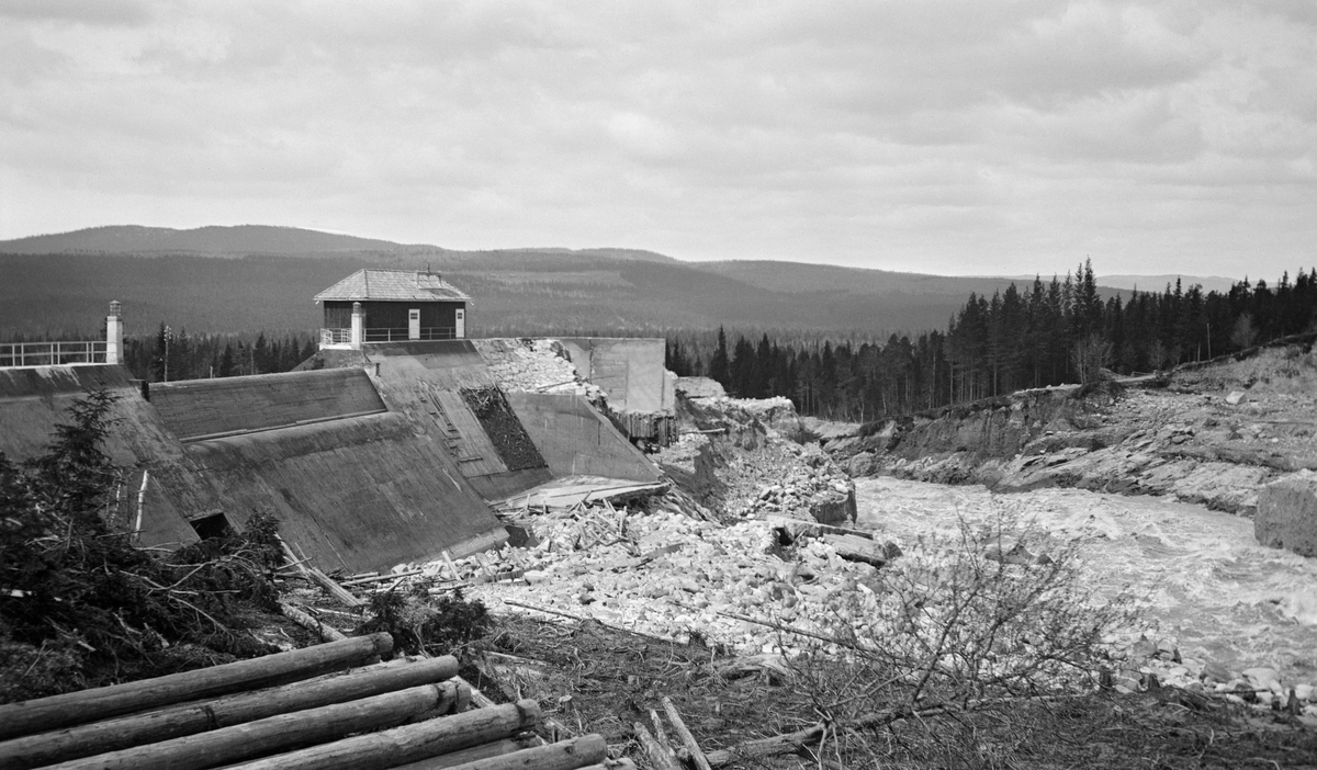 Etter Osfallskatastrofen 12. mai 1916. Fotografiet er tatt mot den nye, men ødelagte kraftverksdammen, der den nordre damarmen brast to dager før dette fotografiet ble tatt.  Følgen var at elva grov seg et nytt løp, samtidig som den førte med seg store mengder sand, grus og stein.  Dette forårsaket store materielle skader og betydelige økonomiske tap for kraftverkseierne, innbyggerne i Åmot kommune og den nye hjørnesteinsbedriften Rena Kartonfabrikk. 

En kort historikk om Osfallsutbygginga og Osfallskatastrofen finnes under fanen «Opplysninger». 