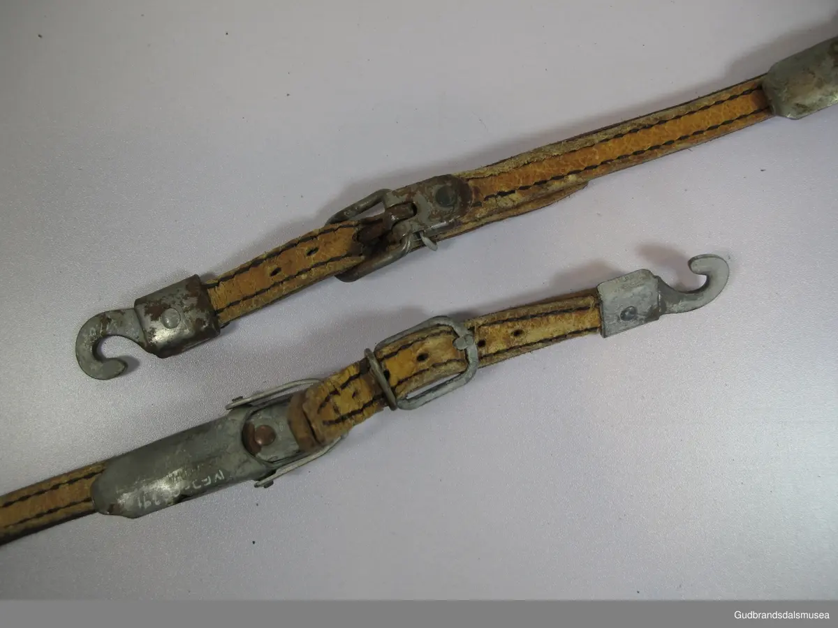 Fire hælbindinger. Gresshoppa, Huitfeldtype med hælbinding i lær kombinert med Høyer-Ellefsen-strammer i metall. Lærbindingene er av dobbelt sammensydd lær i tre deler med metallspenner og festekrok i jern for feste til tåjern.