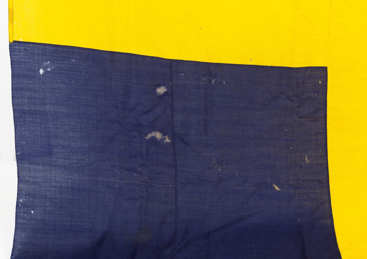 Svensk flagg med unionsmerke, "sildesalaten". Metallhempe. Møllspist og slitt.
Unionsmerket: 120 x 103

Givers datter opplyser at flagget var kjøpt på auksjon eller loppemarked på 1980 tallet. Det skal ha kommet fra båtbyggeriet på Kugrava i Son.