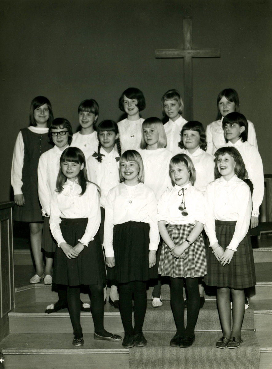 Kållered Missionskyrkas flickkör (födda 1952 - 1958) står i Lilla salen, 1960-tal. Körledare var Ann-Marie Karlsson (ej i bild).
Främst från vänster: 1. Helena Blomkvist. 2. Agneta Ljungström. 3. Eva Benzon. 4. Yvonne Larsson.
Mellersta raden från vänster: 1. Okänd. 2. Ulla Karin Holmberg. 3. Anette Eriksson. 4. Lena Lindgren. 5. Margareta Eriksson.
Bakre raden från vänster: 1. Eva Hällegård. 2. Gunilla Jägrud. 3. Birgitta Wallin. 4. Ingrid Stockman. 5. Katarina Benkel.