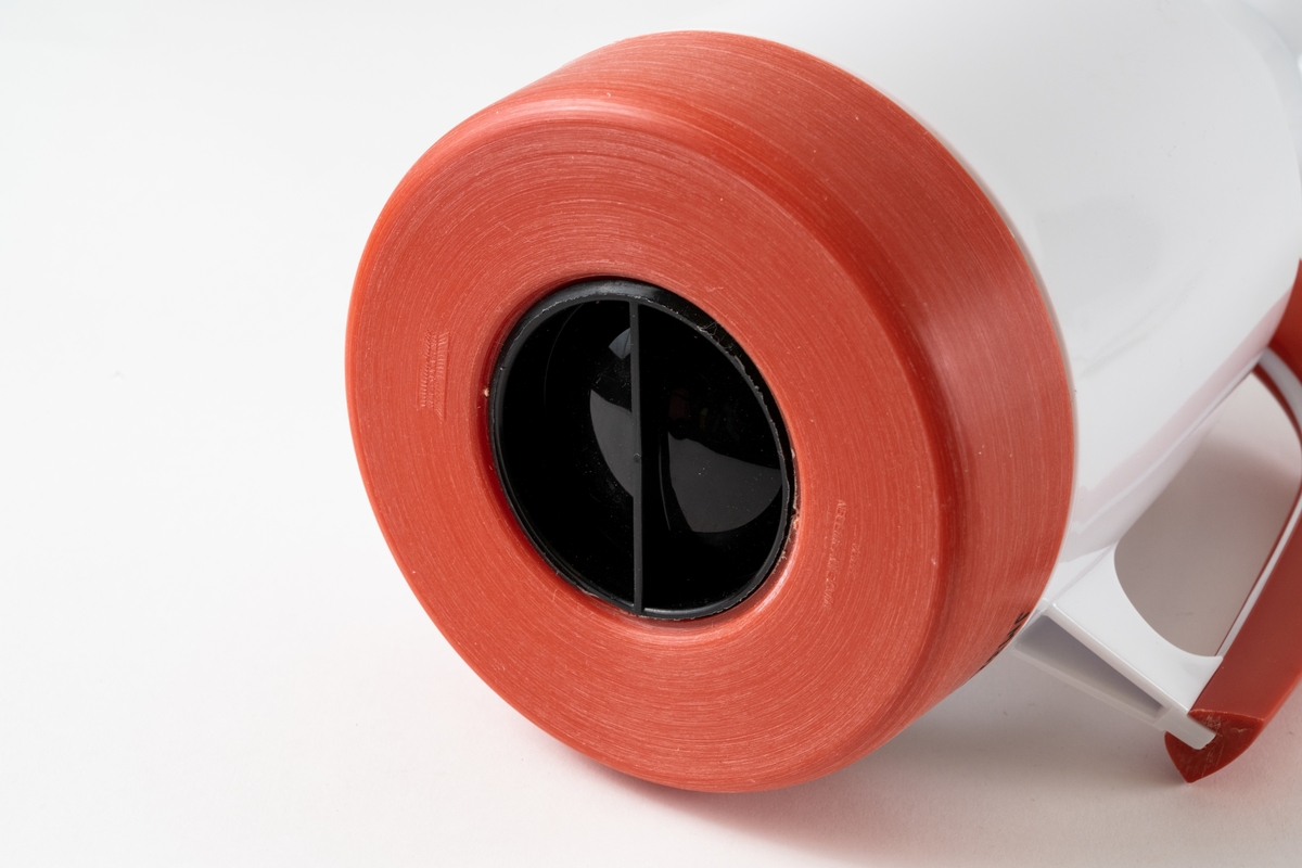 Termoskanna, så kallad TV-kanna, med ytterhölje av vit och orange SAN-plast och innerflaska av glas. Kannan består av expanderkork av plast, tätningsring av gummi, överdel av plast, termosglas, underdel av plast och justerskruv av plast.

Termosen är oanvänd och förvaras i sin ursprungliga plastpåse tillsammans med pappersfolder med bruksanvisning och pappersfolder med VDN varufakta.