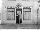 Medfaret fotografi mot Arvid Erikssons frisérsalong i Linköping. Rörelsen startades 1911 av nämnda Eriksson och hans salong låg på adressen Storgatan 18 i nuvarande kvarteret Decimalen. Här ser vi honom tillsammans med en icke identifierad yrkesbroder. Tiden är omkring 1920.