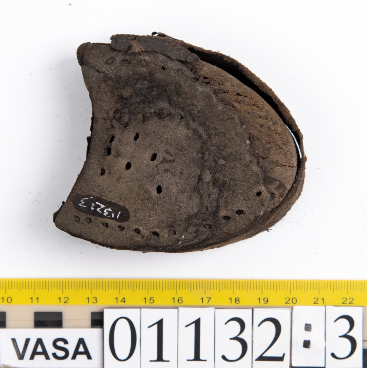 Fem delar av en recent sko.
Sula fyndnummer 01132 har hål efter skopligg och kvarsittande tråd. Sulan är mycket kraftig och välbevarad.
Del av sula, fyndnummer 01123:1, har hål efter skopligg och stygn runt om. Lädret är mycket kraftigt och välbevarat.
En bakkappa fyndnummer 01132:2. På narvsidans mitt samt i nedre kanten finns hål efter stygn. Lädret är mycket kraftigt och välbevarat.
En träklack fyndnummer 01132:3. Klackens kanter omsluts av ett tunt och spaltat lager av läder. Vid den klackkant som är vänd mot hålfoten sitter en kraftig, rektangulär läderbit fästad. På klackens undersida är förstärkt med en kraftig läderbit. Under denna sitter en laglapp. Klacken har kvarsittande träpligg.
En ospecificerad, rektangulär läderbit, fyndnummer 01123:4. Längs med ytterkanterna löper hål. Lädret är kraftigt, narvsidan är dock något spaltad.
