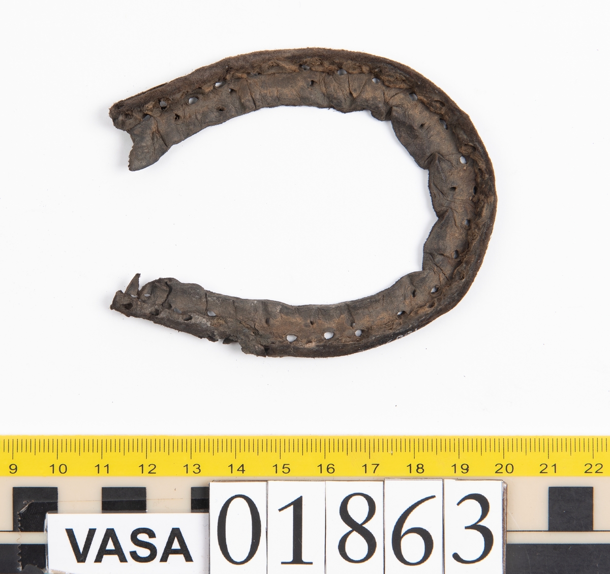 Fyra delar av en sko.
Ovanlädret, fyndnummer 01863, är kraftigt. Strax nedanför tungan finns två snörhål. På ena sidan av ovanlädret har en spricka täckts med en laglapp. Små stygnshål löper längs med kanten på sprickan. Rosettformad mindre öppning i tåpartiet. Ovanlädret är böjt och köttsidan är vänd utåt.
Stropp, fyndnummer 01863:1, har troligtvis varit fästad i skons bakparti eller i sidostycket.
Laglapp, fyndnummer 01863:2, har varit fästad på ovanlädret och täckt en spricka i lädret.
Holtrand, fyndnummer 01863:3, har omslutit delar av bottenlädret.